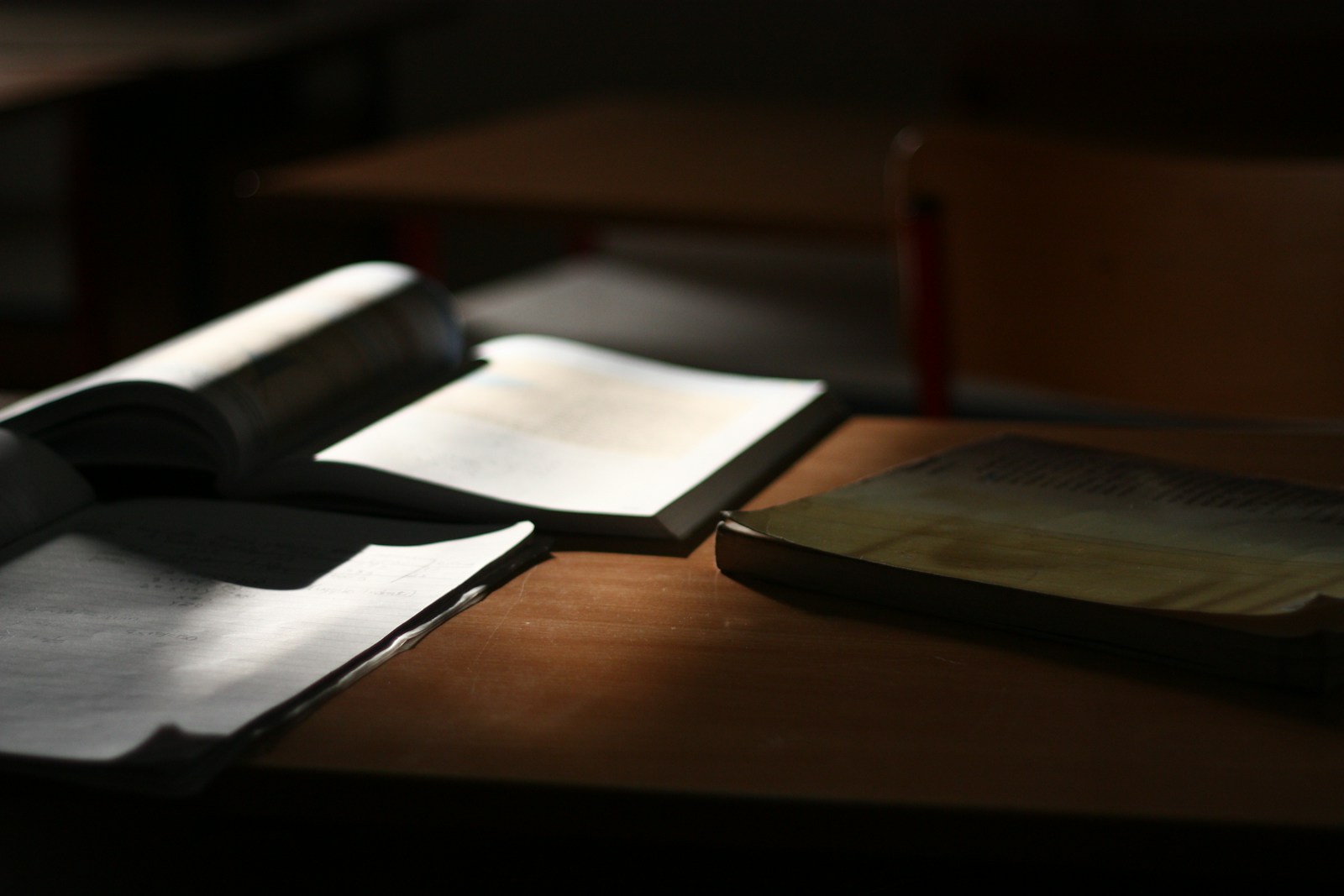 Books sit open on a desk, illuminated by light.